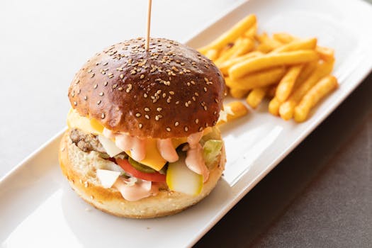 Close-up of a delicious burger with fries on a white ceramic plate, perfect for fast food lovers.