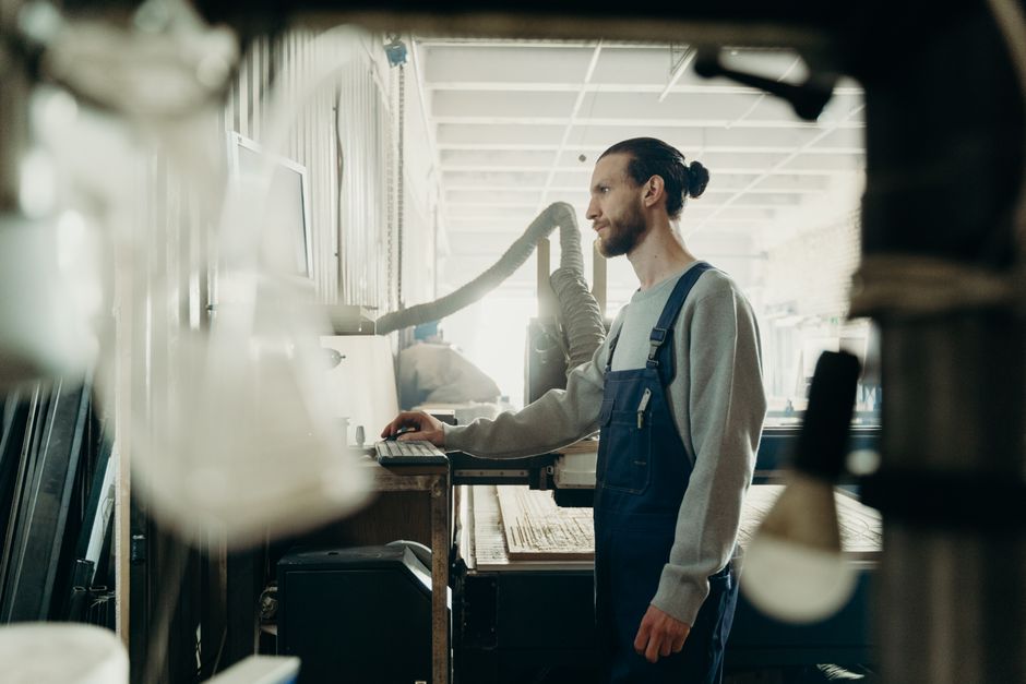 Profile view of a man in denim overalls working in an industrial workshop environment. Profile view of a man in denim overalls working in an industrial workshop environment.