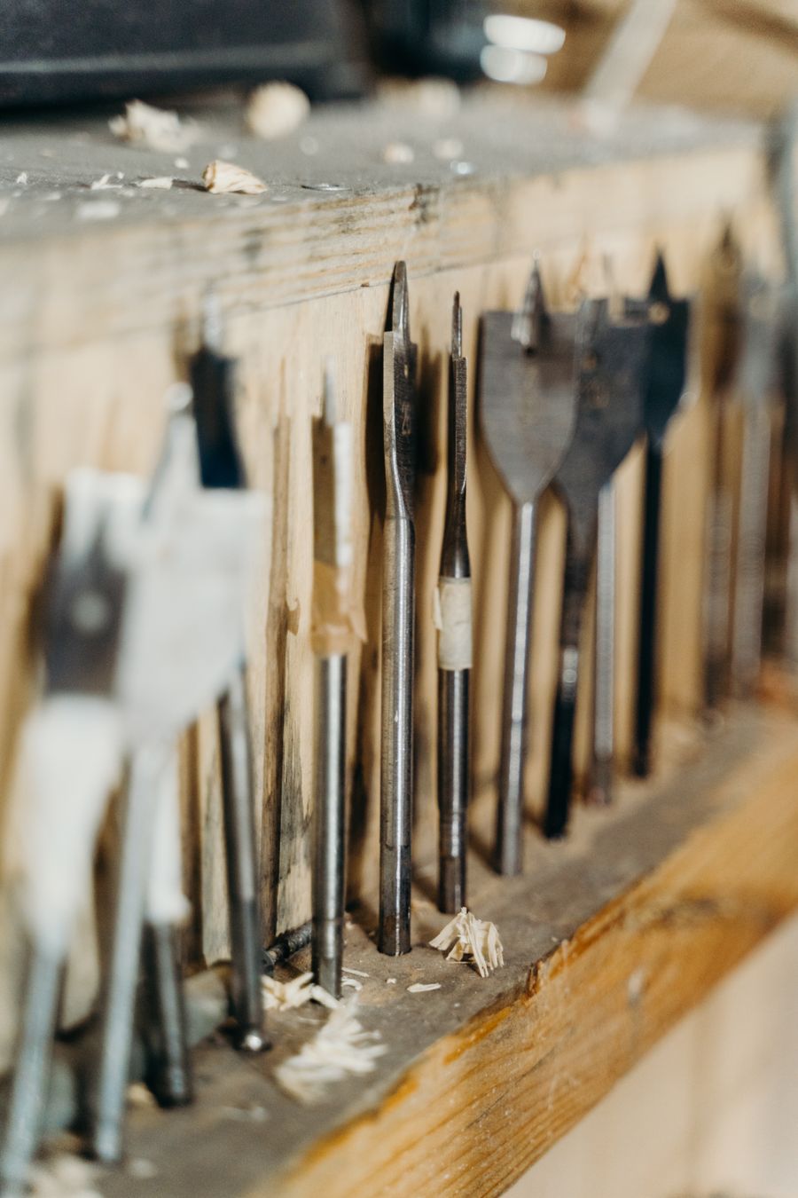 A row of drill bits stored on a workshop shelf