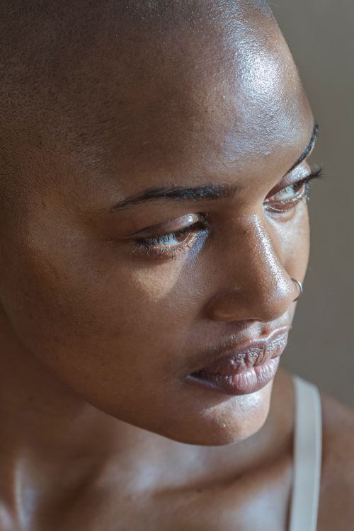 Free Close-up portrait of a bald woman with nose piercing illuminated by natural light. Stock Photo