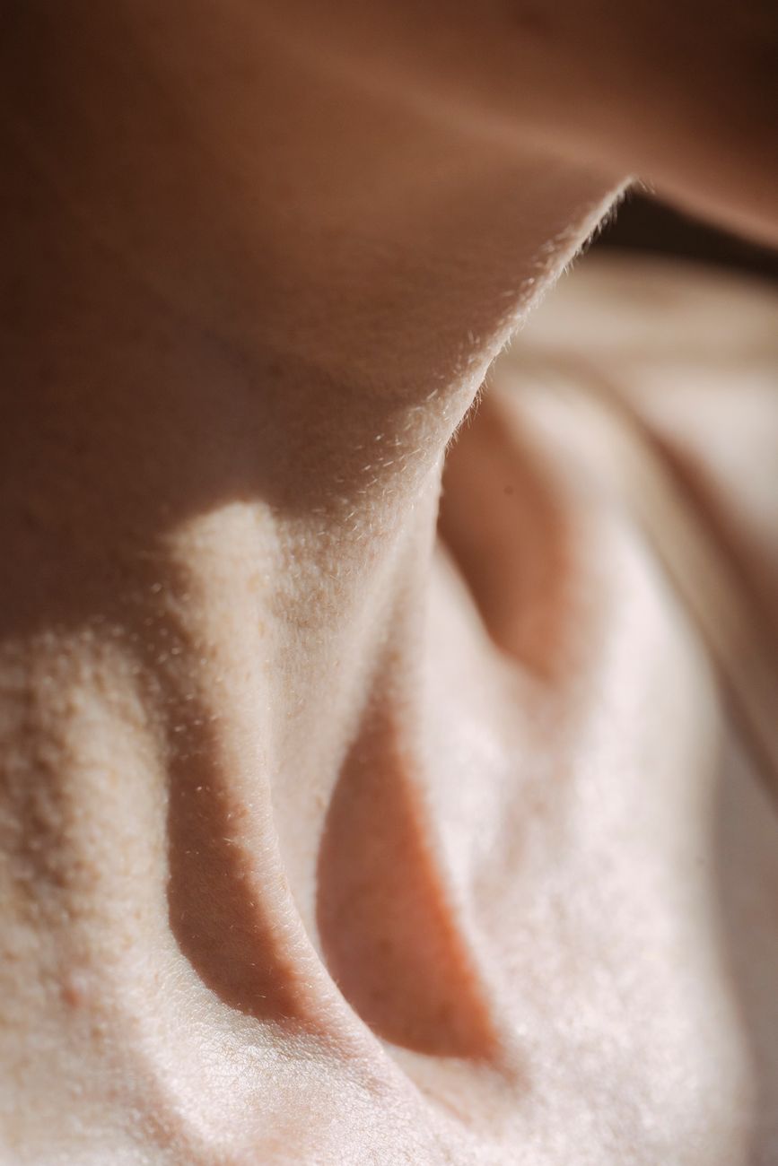 Detailed close-up photo of human neck highlighting skin texture with natural sunlight.