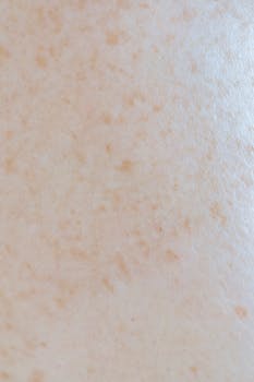 Detailed close-up view of human skin with freckles and texture for skincare concept.