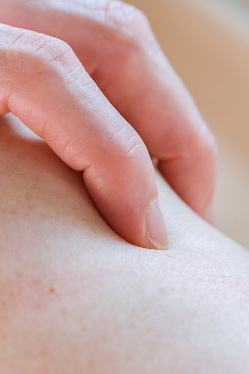 Free Closeup of crop anonymous person touching delicate skin of leg with hand while standing in light room on blurred background Stock Photo