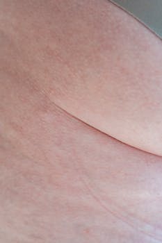 Closeup shot of thigh with lines and butt of crop anonymous plus size female in gray panties standing in light room