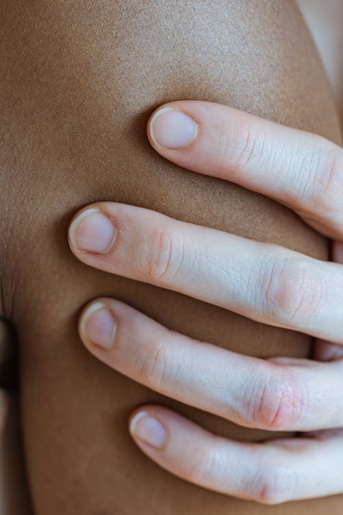 Free Closeup of crop faceless person touching arm of anonymous African American person with smooth skin in light room at home Stock Photo