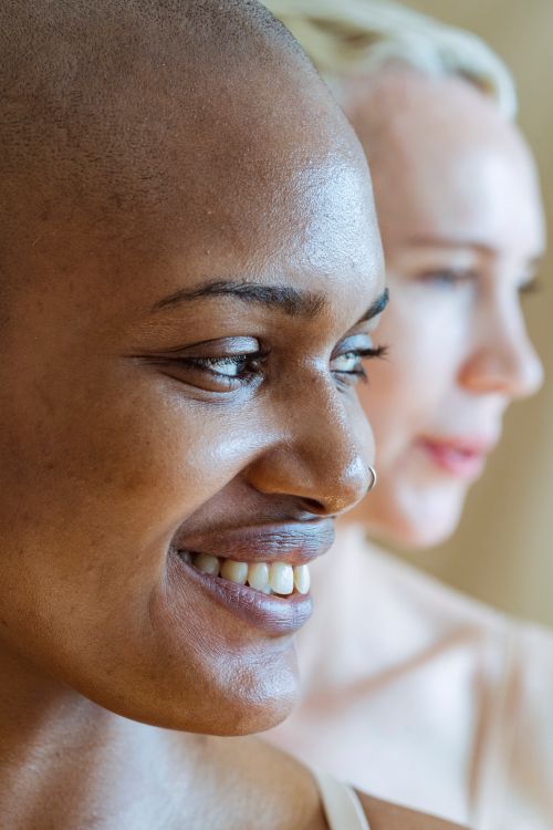 Free Crop positive African American female with piercing near female model with bare skin in studio Stock Photo