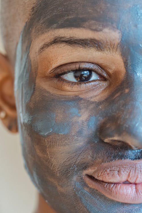 Crop African American female taking care of skin with cleansing clay mask