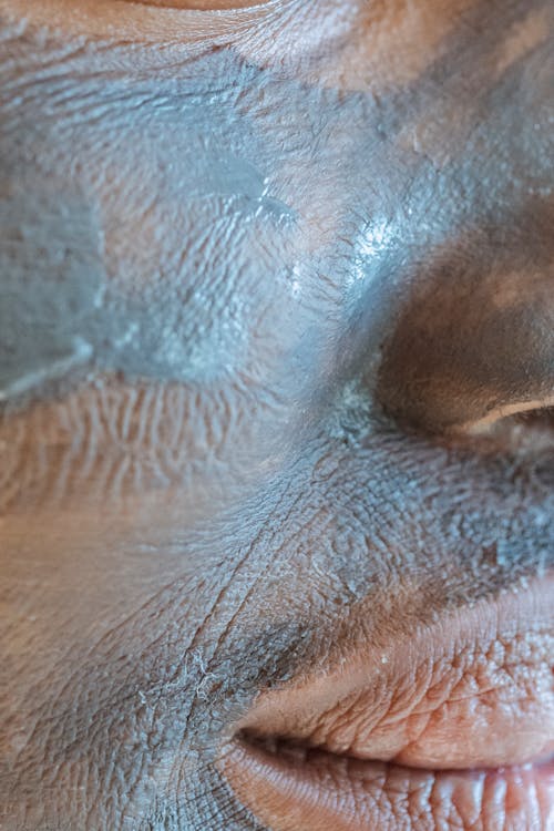 Closeup of crop African American female with smeared clay mask for daily beauty routine