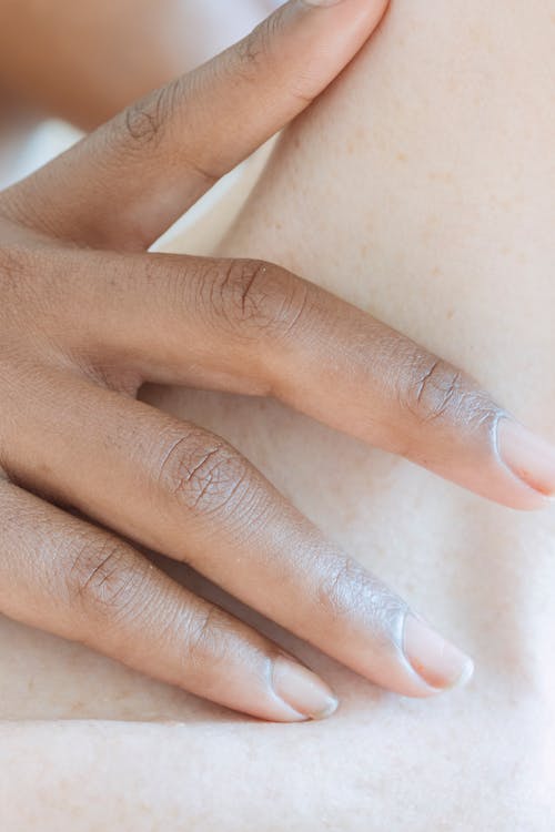 Free Crop anonymous African American female tenderly touching bare skin of woman in daylight Stock Photo