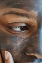 Black woman applying cosmetic mask on face