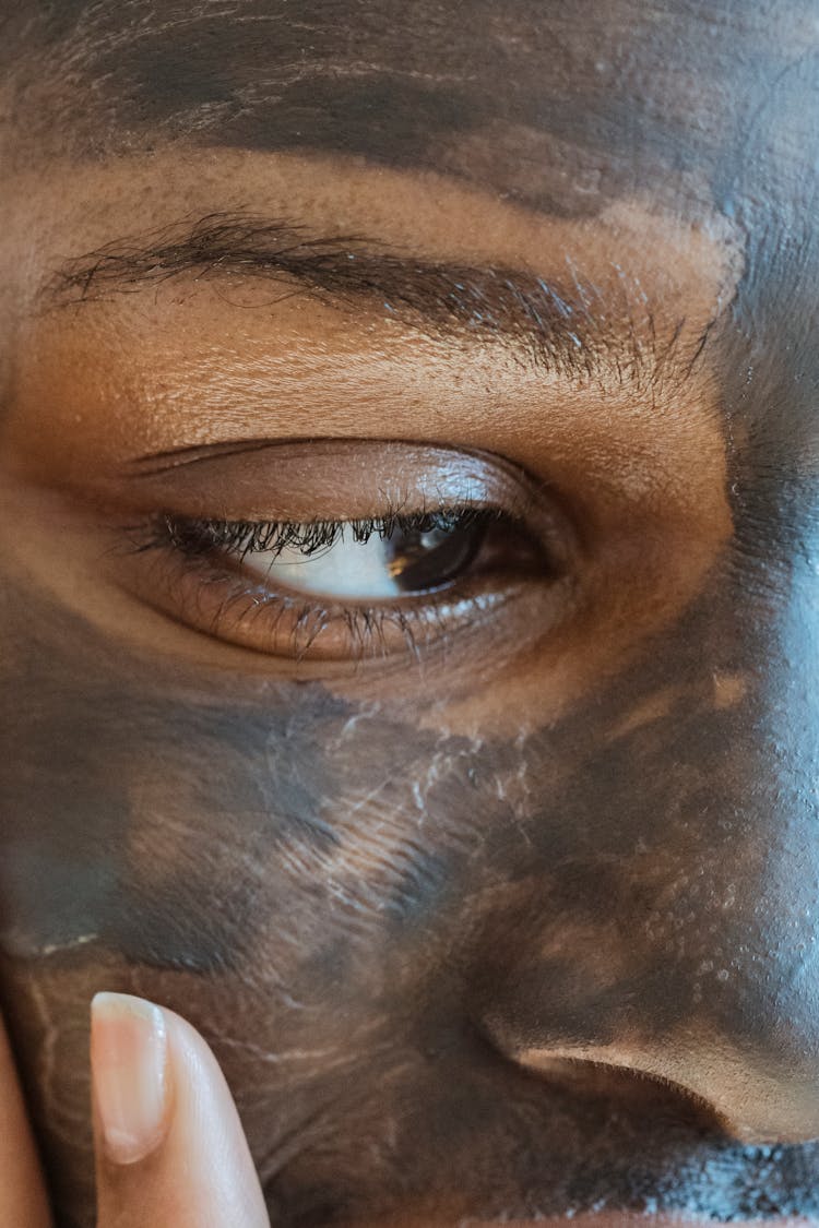 Black Woman Applying Cosmetic Mask On Face