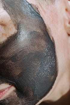Extreme close-up of a person's face with a black clay mask for skincare treatment.