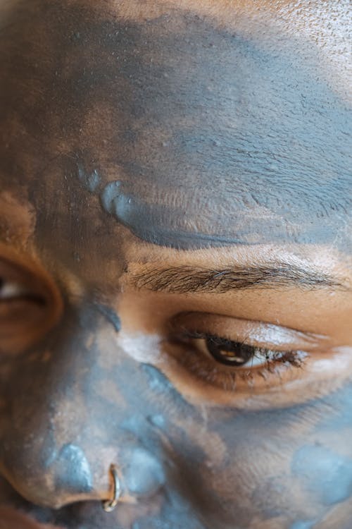 Closeup of crop African American woman with pierced nose and mud mask applied on face