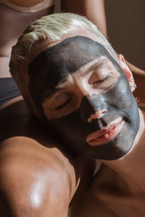 Lady with clay mask on face relaxing on partner leg