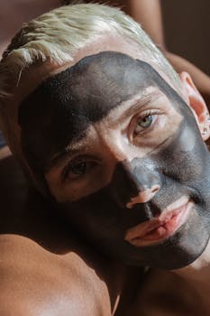 A close-up portrait of a woman wearing a black face mask in natural sunlight.