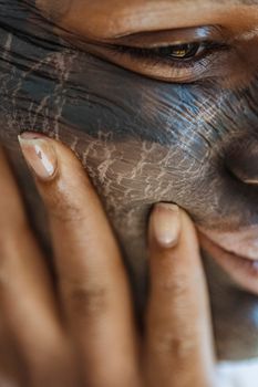 Closeup of crop anonymous African American female with wrinkles and cosmetic mask with lines spots and cracks smeared and dried on face