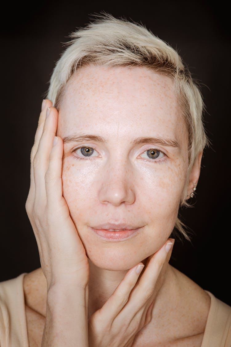 Headshot Of Woman Touching Face On Dark Background