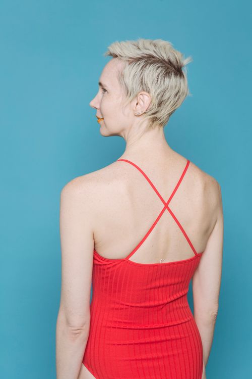 Free Back view of short haired blondie in red bodywear standing on blue background Stock Photo