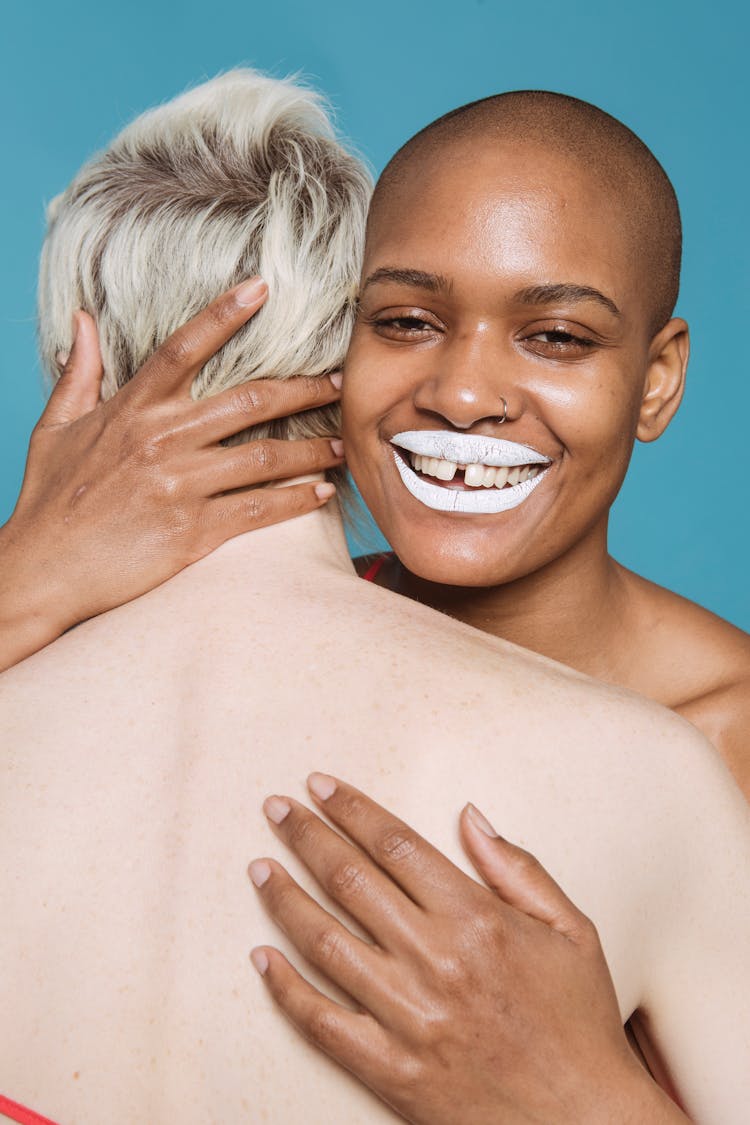 Smiling Multiracial Friends With White Lips Embracing In Studio