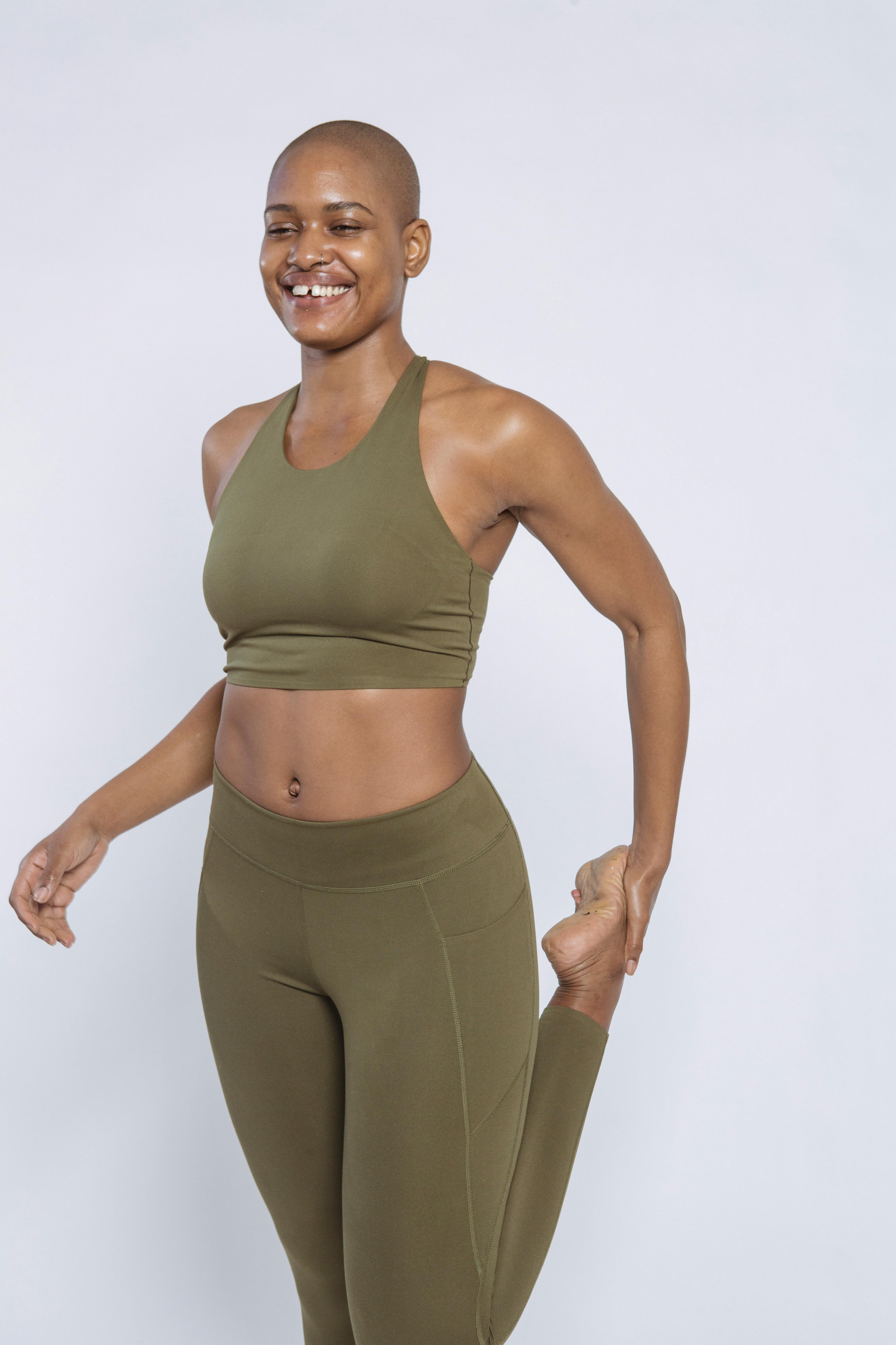 smiling black sportswoman stretching legs in studio