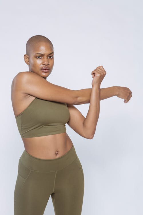 African American sportswoman stretching arms in studio