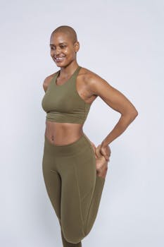 Cheerful woman in olive green activewear doing a yoga stretch in studio.