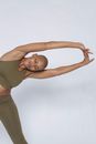 African American female in sportswear with closed eyes bending aside and straightening arms on white background