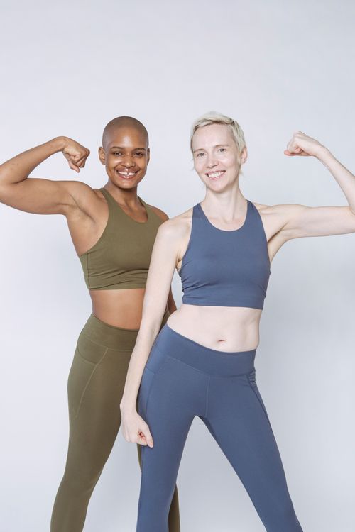 Free Glad slim diverse ladies in sportswear standing with flexed arms and looking at camera on white background Stock Photo