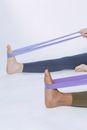 Crop people exercising with elastic purple loops