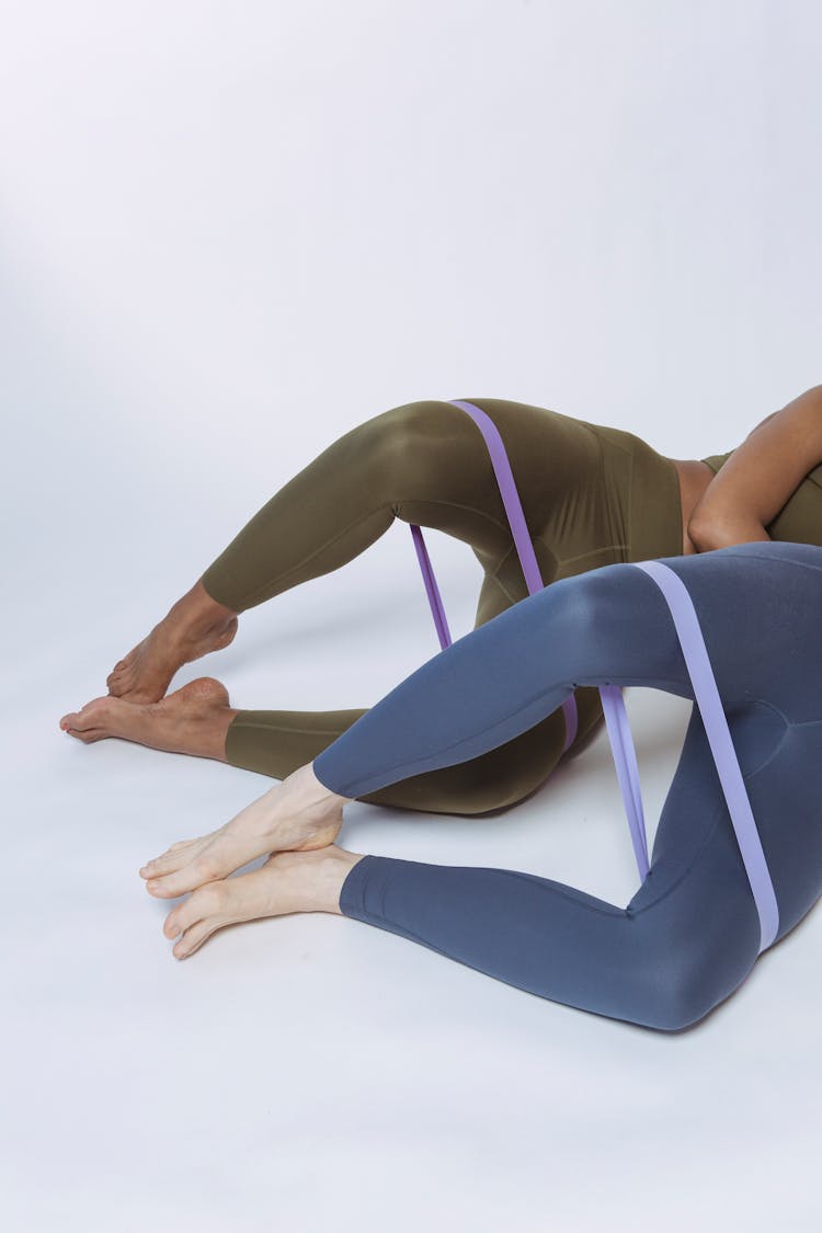 Crop People Stretching Resistance Bands On Floor In Studio