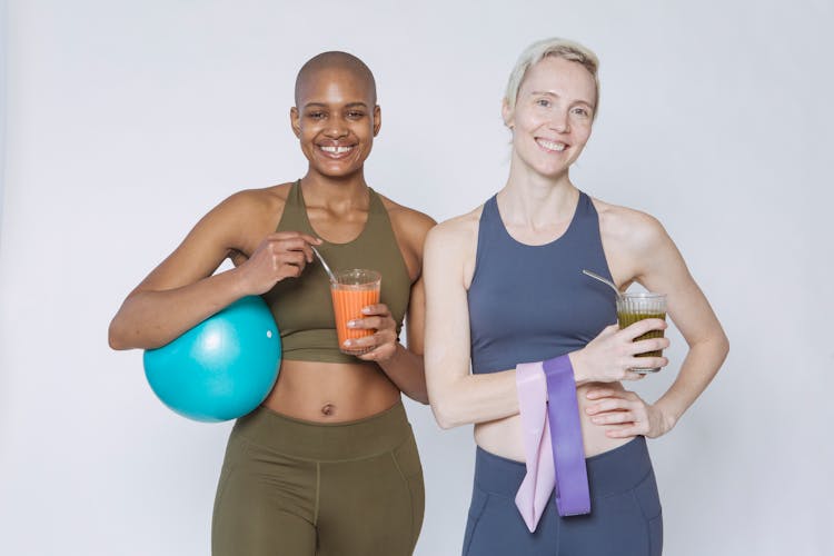 Smiling Diverse Women With Fitness Equipment And Glasses Of Smoothie