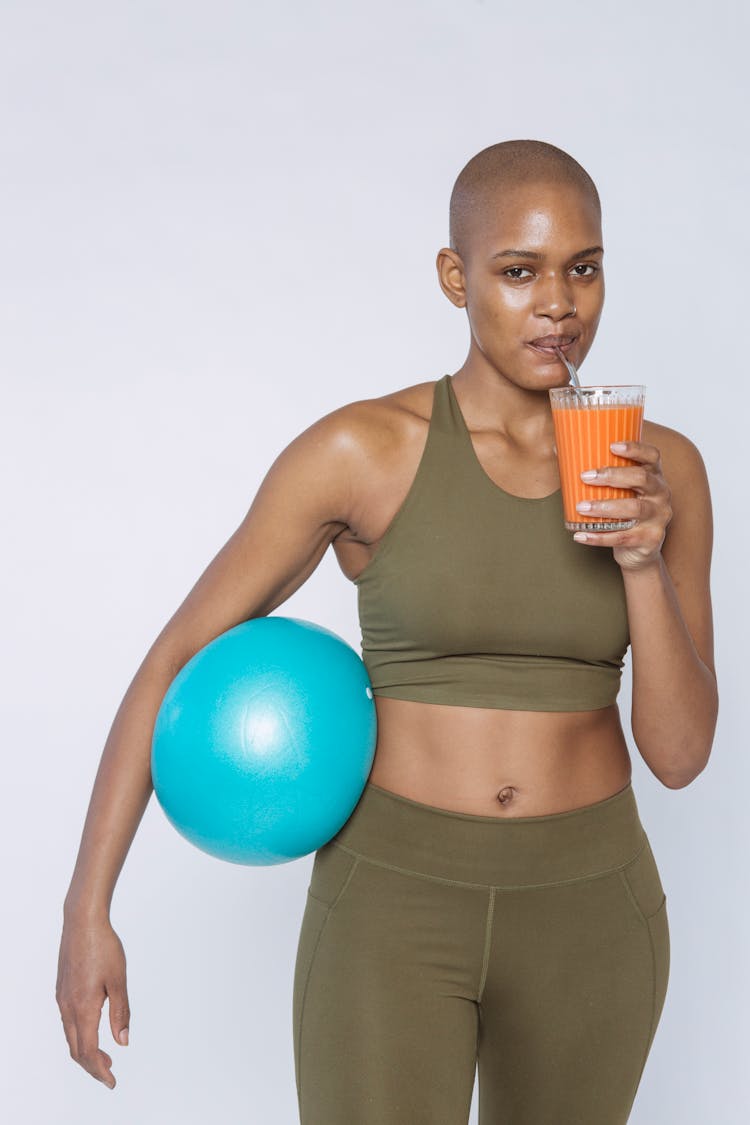 Fit Black Woman Drinking Carrot Smoothie From Straw