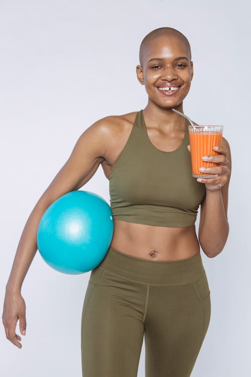 Smiling black woman with glass of carrot smoothie for detox · Free