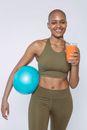 Smiling black woman with glass of carrot smoothie for detox