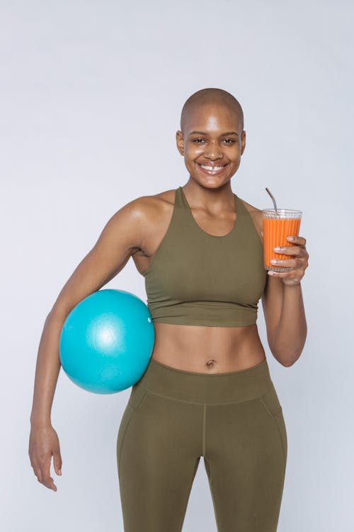 Free Smiling black sportswoman with smoothie and ball Stock Photo