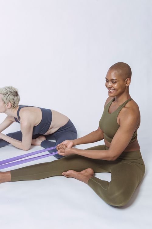 Free Diverse athletes in sportswear practicing fitness exercise with resistance bands during workout in light studio Stock Photo