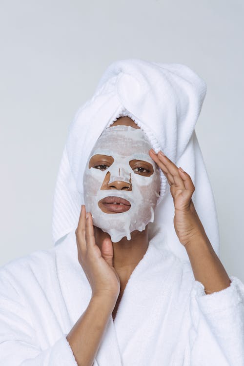 Black woman applying sheet mask on skin