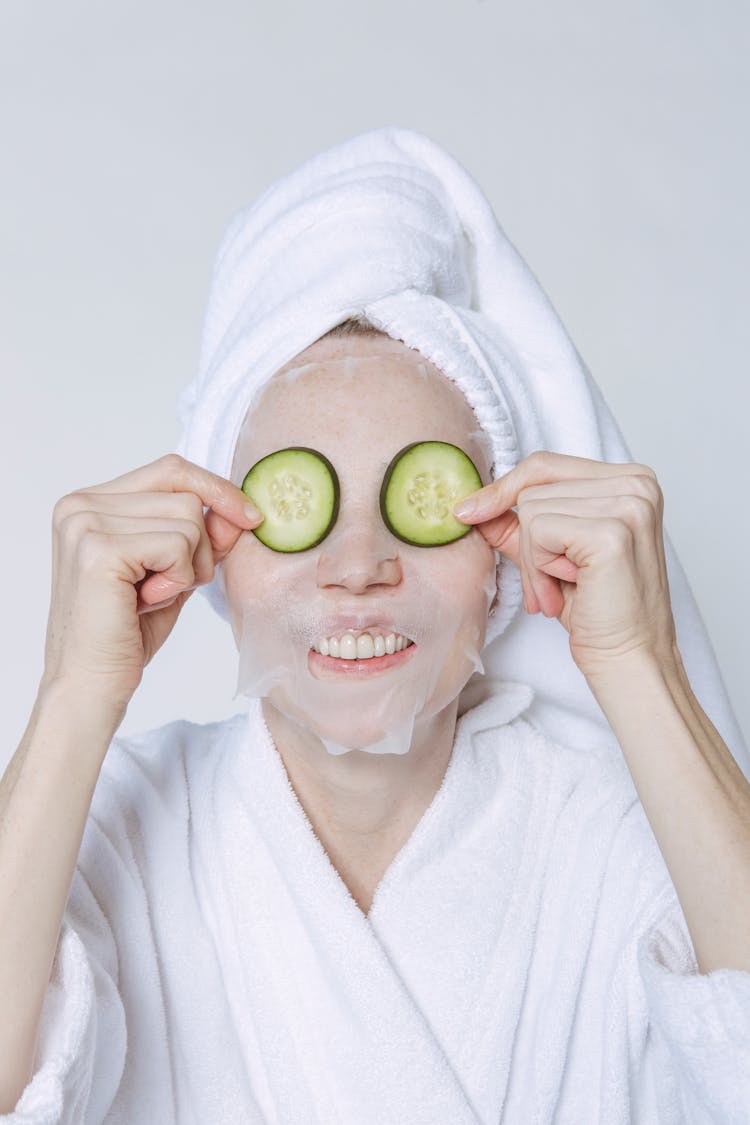 Smiling Woman With Cucumber Slices On Eyelids Over Sheet Mask