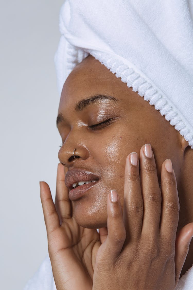 Gentle Black Woman Applying Cream On Face