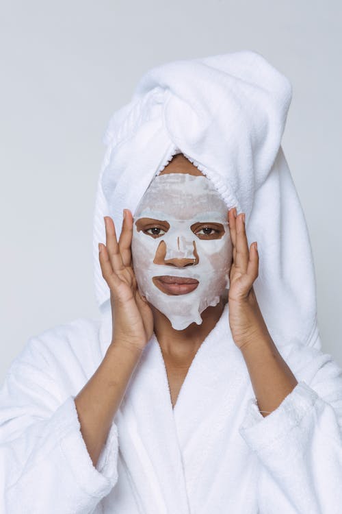 Black woman applying sheet mask in morning