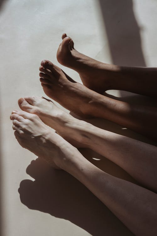 From above of anonymous barefoot diverse crop people lying together on floor in daylight