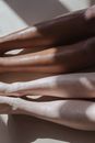 From above of crop diverse unrecognizable people sitting on light flor in sunny day