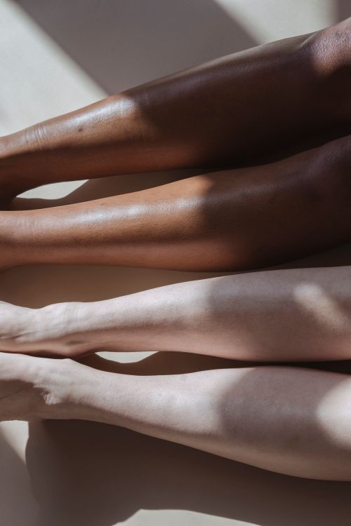 Free From above of crop diverse unrecognizable people sitting on light flor in sunny day Stock Photo