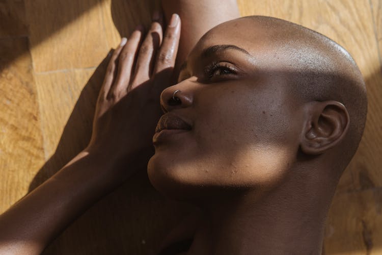 Contemplative Ethnic Model With Piercing Resting On Parquet