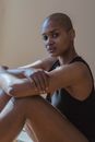 Side view of African American female with folded arms looking at camera on beige background