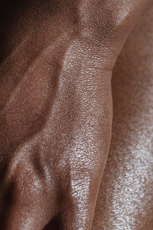 Free Closeup of crop unrecognizable ethnic person with veins on hand touching glowing body skin Stock Photo