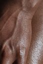 Closeup of crop unrecognizable ethnic person with veins on hand touching glowing body skin