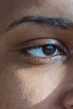 Closeup of crop ethnic person with shade on imperfect skin looking away in light ray