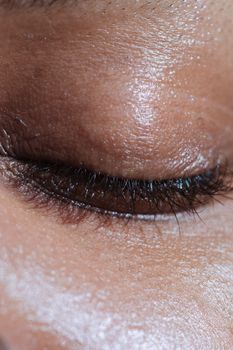 Closeup of crop anonymous ethnic person with long eyelashes and shiny delicate skin in light ray