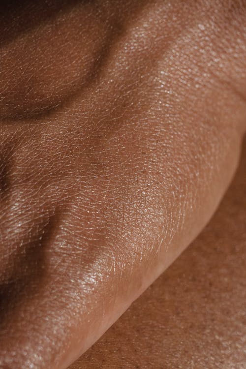 Closeup full frame hand of crop anonymous person with veins and smooth skin placed on leg in light room at home